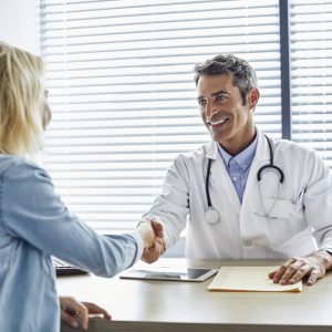 Doctor shaking hands with woman at hospital