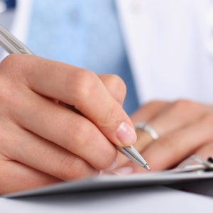 Female doctor arm hold silver pen and pad during ward round check closeup. Medic exam aid visit and remedy prescribe for sick office business visitor with problem and complaint for anamnesis concept